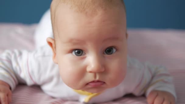 Doordachte baby attentevly kijken naar de camera. Close-up van portret — Stockvideo