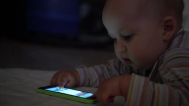 Bebek smartphone ile çalış ve ekran dokunur. Yüzü mavi ışık. El atış