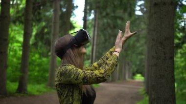 Vr kulaklık kadında eller tarafından hava dokunur. Ağaçları arasında sanal gerçeklik
