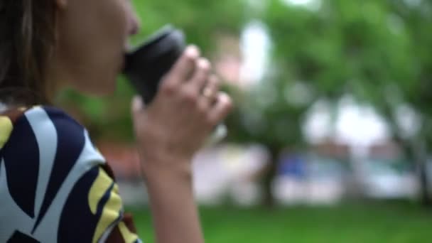 Tjej dricker takeaway kaffe medan du går ner på gatan. Kort skärpedjup — Stockvideo