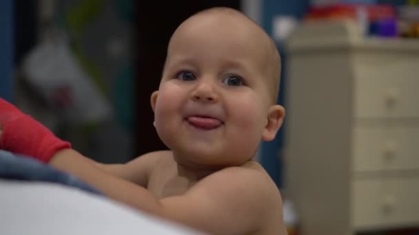Happy baby with red bandage on his hand shows tongue and laughes. Handheld slow motion shot — Stock Video