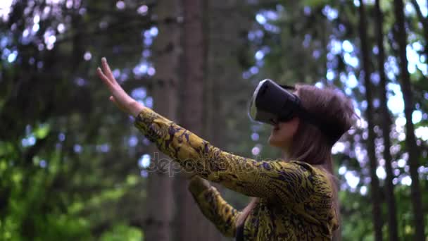 Frau im vr-Headset blickt zu den Objekten in der virtuellen Realität auf und streckt die Hände aus — Stockvideo