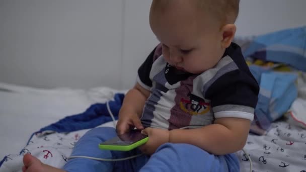 Baby bezit in handen smartphone en duwt knop met een vinger. Handheld schot — Stockvideo