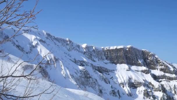 Branta sluttningar i Kaukasus täckt med snö. Klarblå himmel över Klippiga bergen. Handhållna skott — Stockvideo