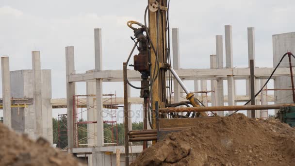 Mobilní vrtná souprava pracuje na staveniště. Betonové konstrukce jako pozadí — Stock video