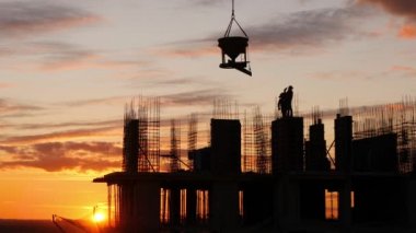 İnşaat sitesi agains gün batımı gökyüzü silüeti. Beton ekipmanları vinç asansörleri Warkers beklemek
