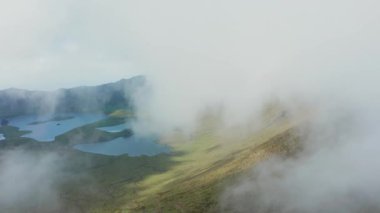 Volkanın tepesindeki bulutta uçuyor. Caldeirao, Corvo, Azores 'in yeşil yamaçları ve gölleri.