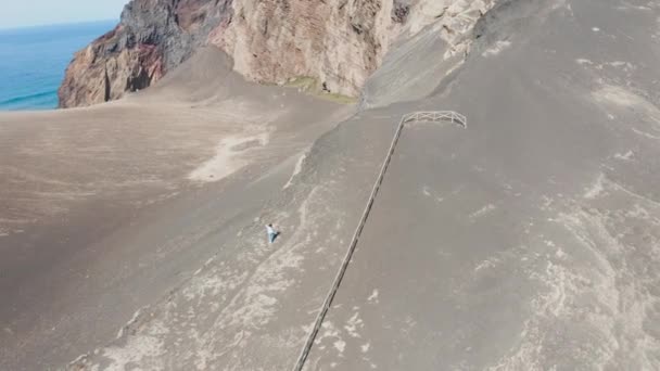 Mała figura kobiety na krawędzi skalistego klifu. Turysta robi zdjęcie krajobrazu — Wideo stockowe