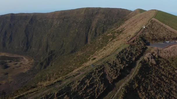 Twee vrienden lopen langs het pad rond de grote caldera van inactieve vulkaan Cabeco Gordo. Luchtfoto van Faial, Azoren — Stockvideo
