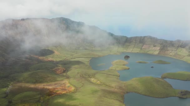 구름 속 산등성이의 꼭대기. 산 기슭의 푸른 들판 과 호수. 공중에서의 간헐천,아 조레스 — 비디오