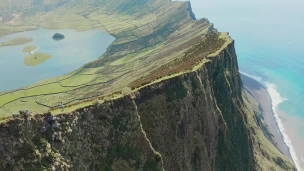 Woman walks along the edge of steep cliff of huge inactive volcano. Aerila of Caldeirao, Corvo, Azores — Stock Video