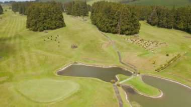 Küçük göletli, ağaçlı ve yeşil çimenli golf sahası. Rüzgarlı San Miguel adası, Azores