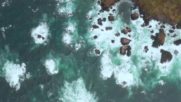 Vista superior de mares agitados. Las olas se precipitan en las rocas costeras en salpicaduras blancas. Foto aérea del océano Atlántico — Vídeo de stock