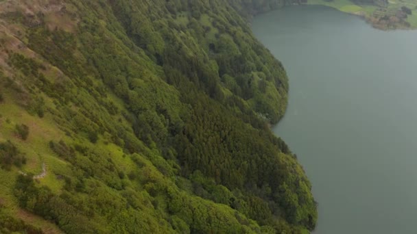 Απότομες πλαγιές ηφαιστειακής καλντέρας καλυμμένες με πράσινα δέντρα. Βουνό πάνω από λίμνη. Aerial of Sete Cidades volcano, San Miguel, Αζόρες — Αρχείο Βίντεο