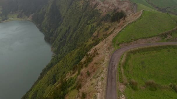 Lake in volcano caldera. Steep slopes of crater and road on the top of ridge. Aerial of Sete Cidades volcano, San Miguel, Azores — Stock Video