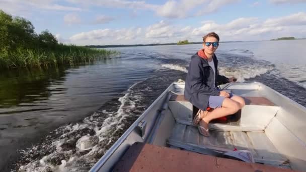 Mann steuert Motorboot vom Heck aus Mann fährt Motorboot auf sonnigem See — Stockvideo