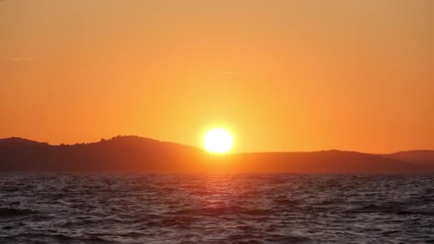 El sol se pone en el mar. Las olas y salpicaduras brillan en la luz del atardecer. Colores brillantes — Vídeos de Stock