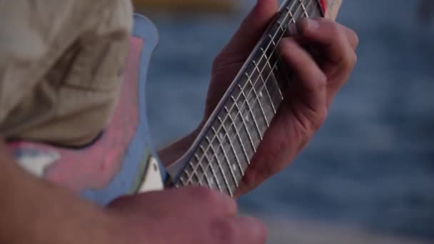 Dedos en diapasón de guitarra eléctrica. El músico canta una canción al aire libre. Primer plano. — Vídeos de Stock