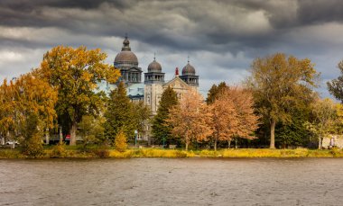 Arka planda antik yapı kubbeleri olan nehir kıyısındaki sonbahar parkının manzarası