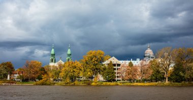 Arka planda antik yapı kubbeleri olan nehir kıyısındaki sonbahar parkının manzarası