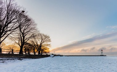 Donmuş deniz kıyısındaki güzel deniz fenerinin kış günbatımında çekilen manzarası.