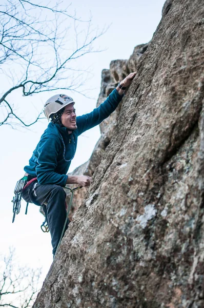 深刻な顔をした登山家が崖の端に沿って登ります — ストック写真