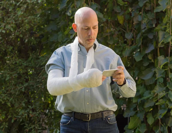 Ung man med en arm gjuten textning på sin telefon — Stockfoto