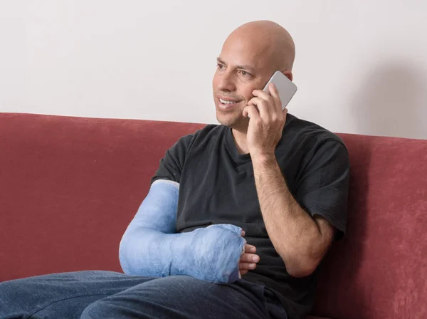 Joven con un brazo fundido hablando en su teléfono —  Fotos de Stock