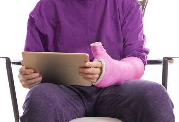 Pessoa com gesso de braço usando um comprimido acessível — Fotografia de Stock