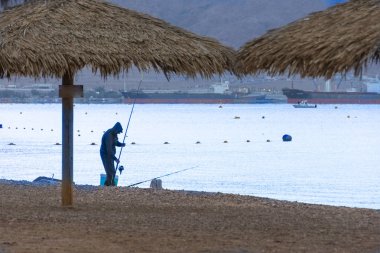 Man fishing at the Red Sea, on the beach of Eilat, Israel clipart