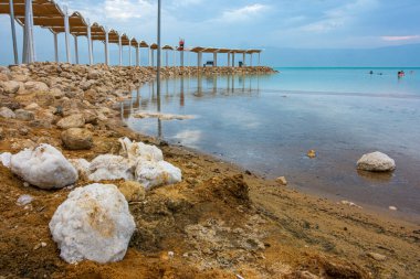 Ölü Deniz 'in güneş doğmadan önceki mavi saatindeki yaratıcı görüntüsü. Denize ve tuz oluşumlarına doğru yükseltilmiş bir yürüyüş yolu.