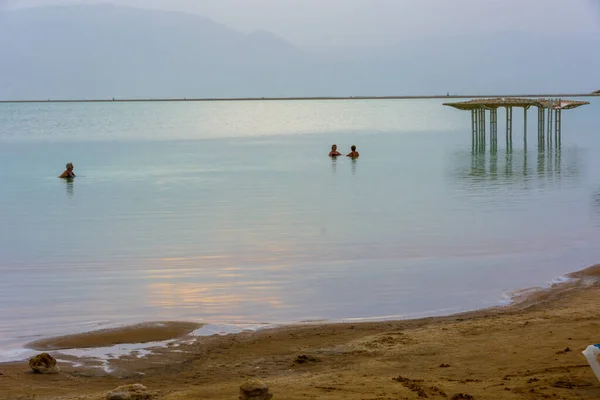 Elderly people ejoying the warm waters of the Dead Sea at the blue bour before sunrise