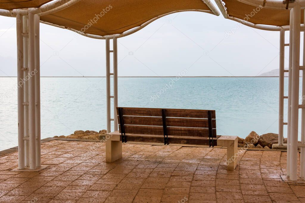 Creative image of the  Dead Sea at dawn blue hour before sunrise, featuring a bench overlooking the sea