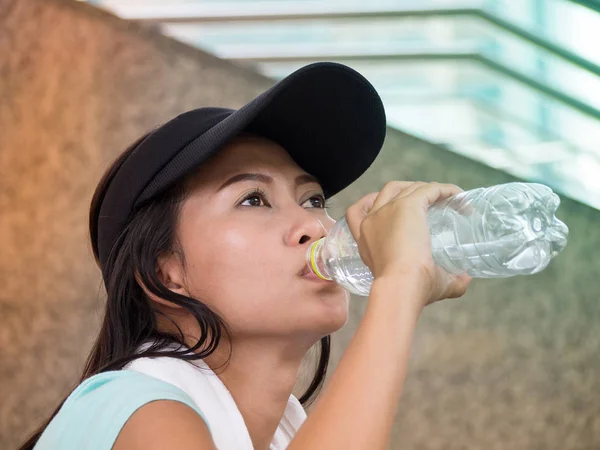 İş bittikten sonra Asyalı kadın portresi thirstily, suyu içer.