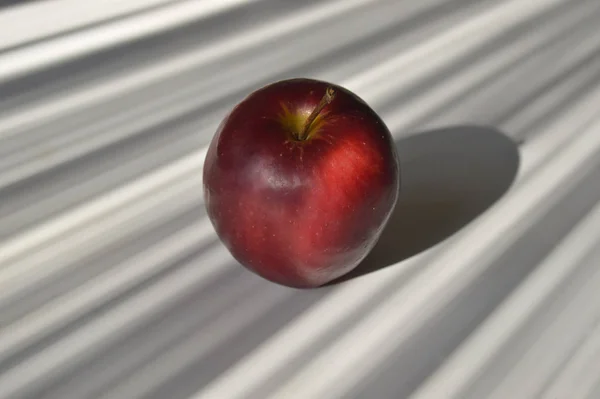 Big red apple on striped dark gray and light gray background