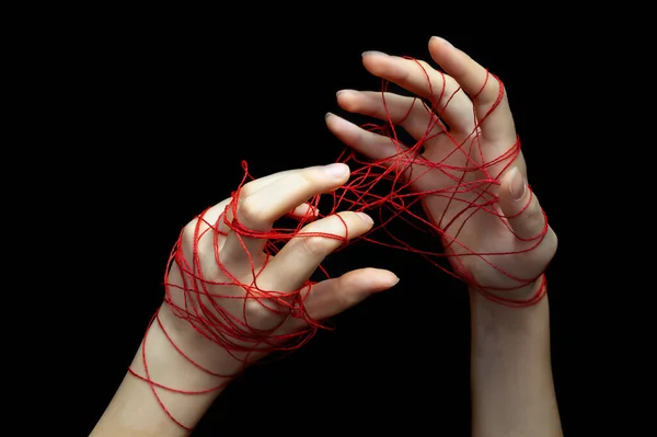 Two female hands entangled in a network of red social media threads on a black isolated background.Selective focus.The concept of social networks, social dependence. — Stock Photo, Image