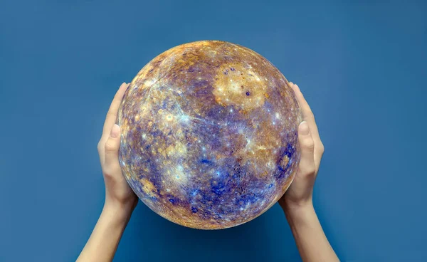 The concept of the world is in your hands. Two female hands hold a globe on a blue isolated background.Elements of this image are provided by NASA. Copy space, top view, selective focus.
