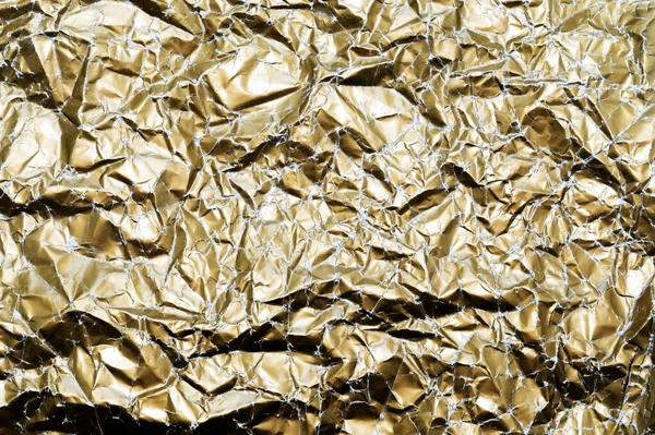 Gold background of crumpled paper. Close-up of a gold leaf with a mint, uneven surface.The view from the top. Fashion trend of the year-vintage gold. Abstract texture background, space for copying