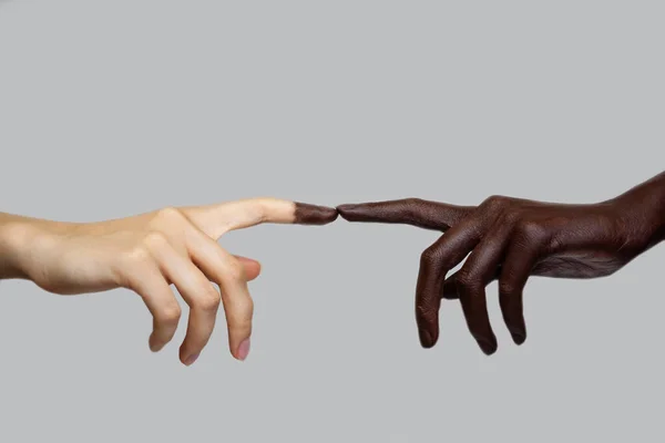 İki siyah ve beyaz el, gri izole bir arka planda parmaklarıyla birbirine dokunur. Irklar arası arkadaşlık ve saygı kavramı. Irkçılıkla mücadele