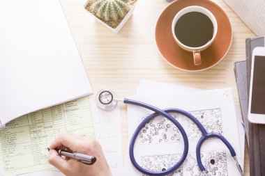 Görünümü doktor office fincan kahve, stetoskop, ekg kağıt ile top, el kanı test sınavı ve boş belge