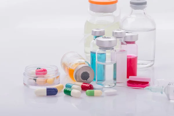 Пробирки со шприцем и капсулой с таблетками на белом столе медицинская концепция — стоковое фото