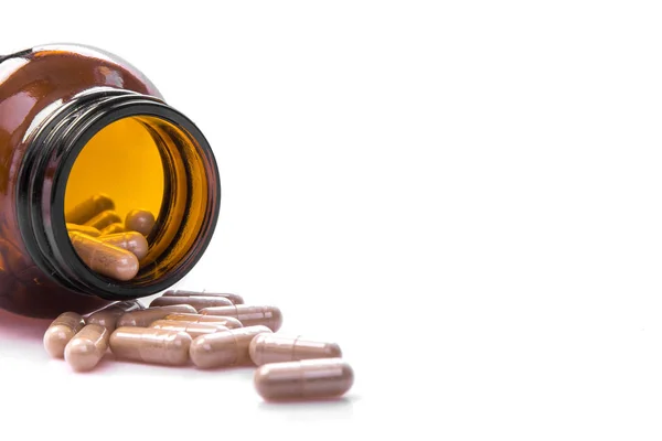 Ліки таблетки капсули зі скляно-коричневою пляшкою на білому столі медична концепція — стокове фото