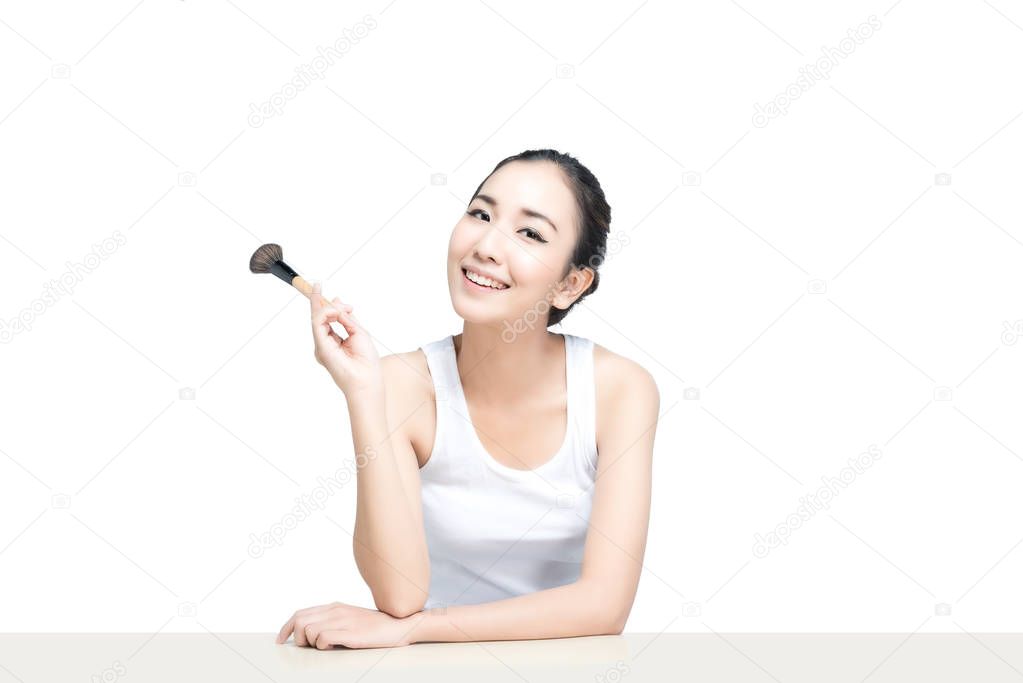 Asian woman with beautiful skinface non make up,pure cosmetic holding brush on white background
