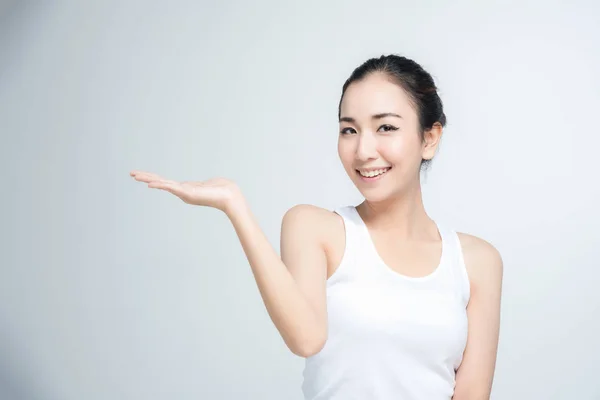 Asyalı genç kadın güzel gülümseme ile duruş mevcut beyaz arka plan üzerinde boş elinde bir şey — Stok fotoğraf