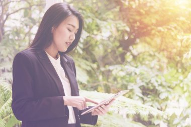 Tablet yaslanmış stand relax için pencerenin yanında kullanarak zarif genç iş kadını ekrana bakarak