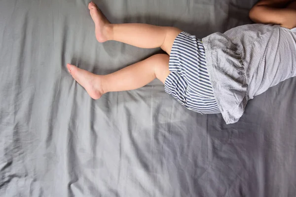El niño orina en un colchón, pies de niña y orina en la sábana, concepto de desarrollo infantil, enfoque seleccionado en húmedo en la cama —  Fotos de Stock