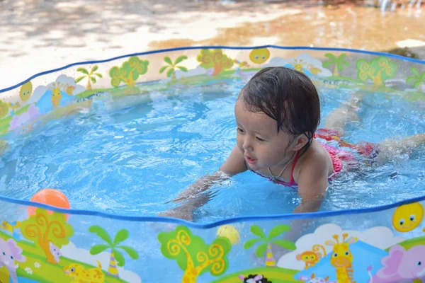 Cute happy baby laughing playing inside of little plastic bath in the garden on a hot summer day without parent moderator — Stock Photo, Image