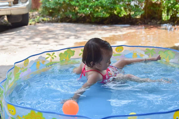 Lindo bebé feliz riendo jugando dentro de un pequeño baño de plástico en el jardín en un día caluroso de verano sin moderador de padres —  Fotos de Stock