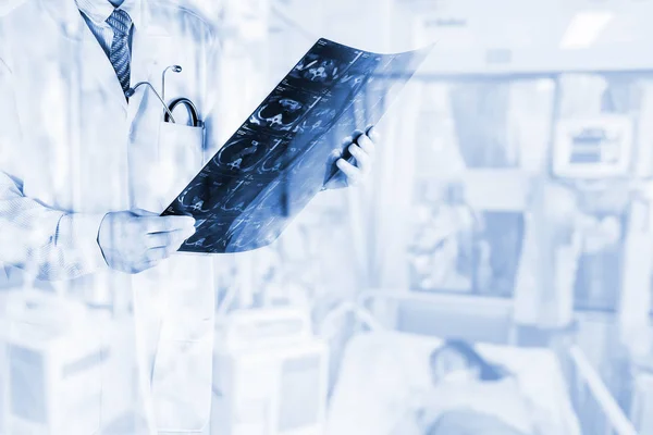 Врачи просмотра пленки рентгеновского снимка пациента с размытым пациентом в больничной палате, концепция медицинского фона — стоковое фото