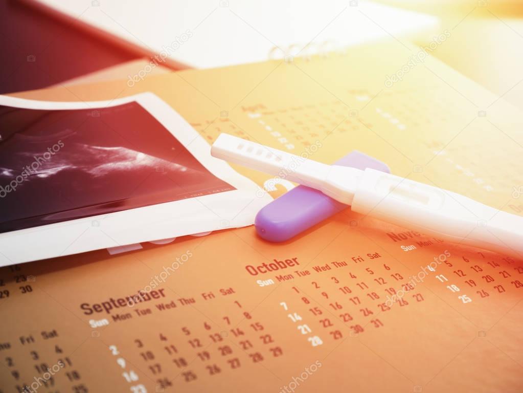 pregnancy test on calendar with ultrasound background
